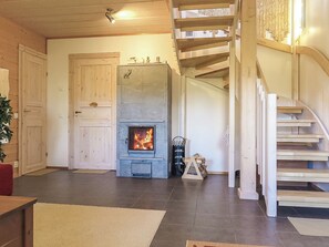 Un salon spacieux avec une cheminée, un escalier en bois et une porte.
