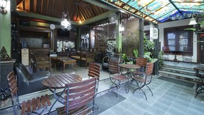 A restaurant with wooden furniture, a tiled floor, and a colorful stained glass ceiling. - OYO 804 Ndalem Maharani Guest House (Yogyakarta)