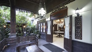 A traditional wooden interior with a bench, a chandelier, and a dining area. - OYO 804 Ndalem Maharani Guest House (Yogyakarta)