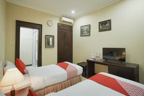 A hotel room with two beds, a TV, a desk, and a wardrobe. - OYO 804 Ndalem Maharani Guest House (Yogyakarta)