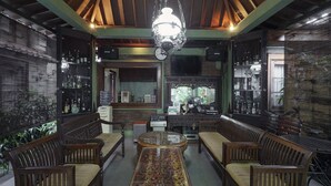 A traditional interior with wooden furniture, a central glass-top table, and a hanging light fixture. - OYO 804 Ndalem Maharani Guest House (Yogyakarta)