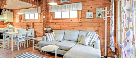 A cozy cabin interior with a dining area, a sofa, and a striped rug.