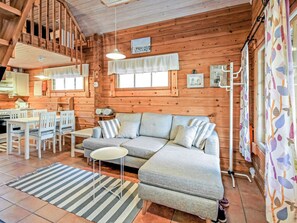 A cozy cabin interior with a dining area, a sofa, and a striped rug. - Marjatan mökki by Interhome (Enontekiö)