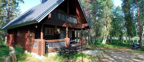 A cabin with a porch, a chimney, and a deck.