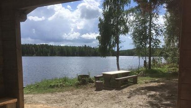 A wooden deck leading to a lakeside picnic area with a bench and table.