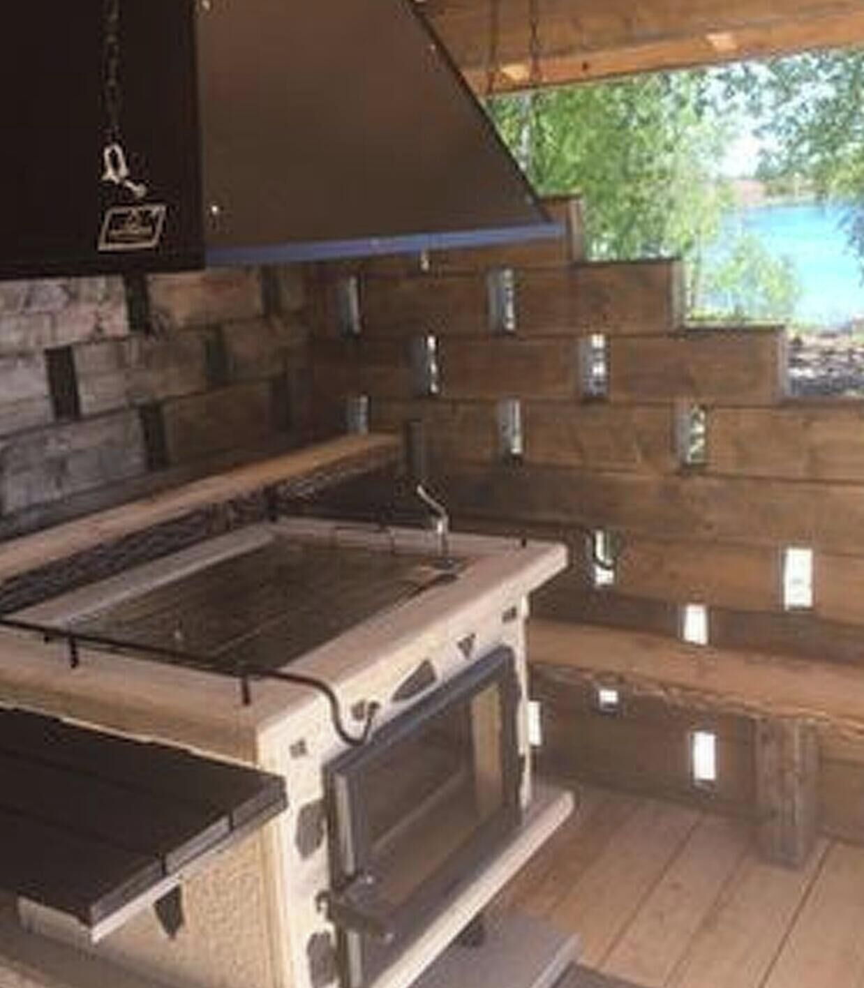 A wooden outdoor kitchen with a grill and a built-in oven.