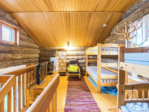 A log cabin room with bunk beds, a television, and a window.