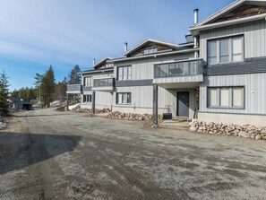A modern two-story building with a stone foundation and a gravel driveway.