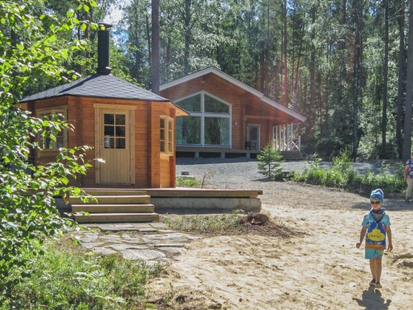 A cabin with a stone pathway leading to the entrance, surrounded by a forest.