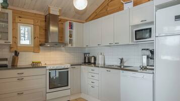 A modern kitchen with white cabinets, stainless steel appliances, and a wooden ceiling.