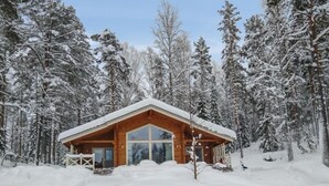 Une cabane en bois entourée d’arbres couverts de neige.