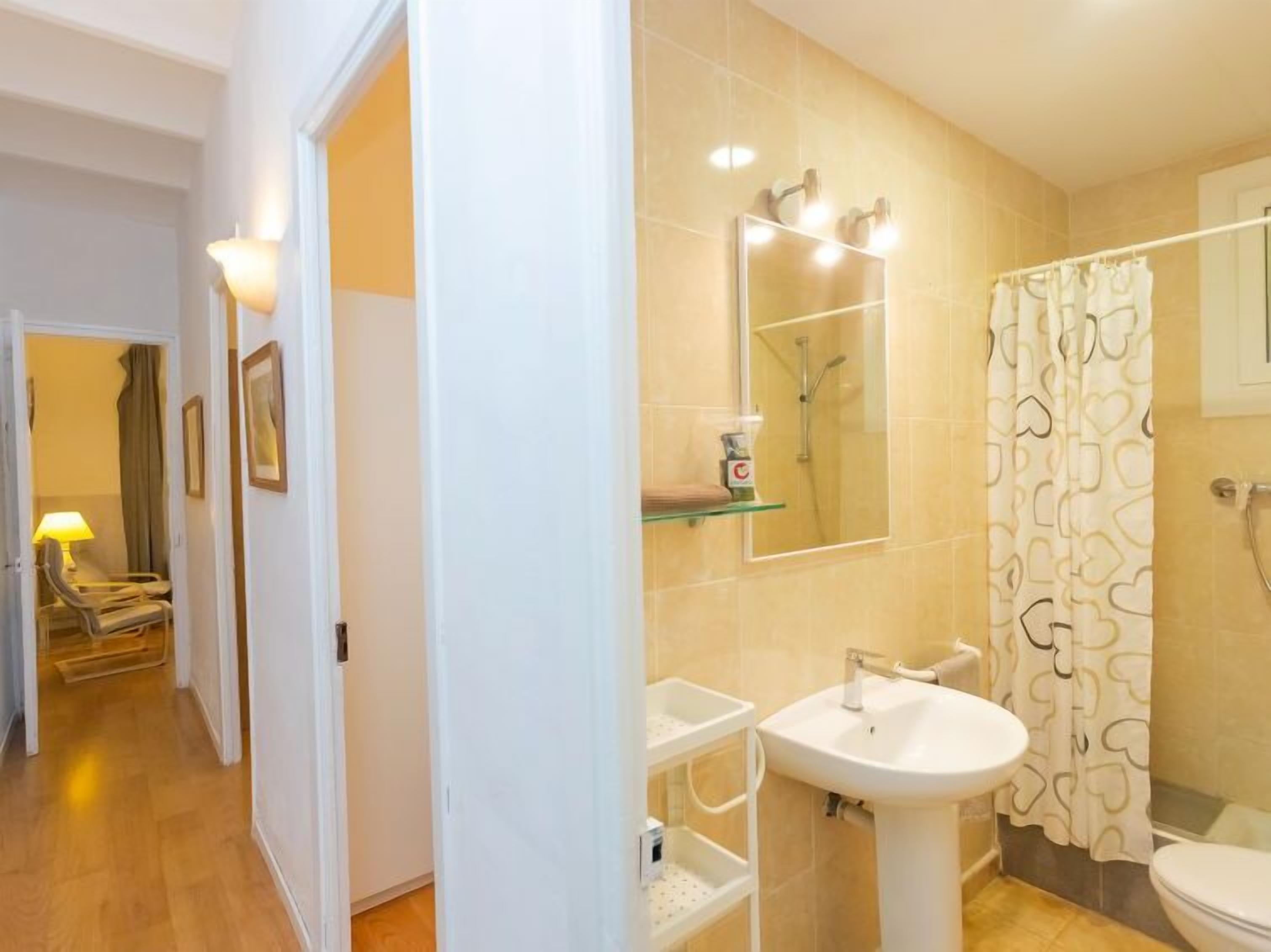 A modern bathroom with a glass shower enclosure, a white sink, and a toilet.