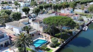 Un quartier résidentiel doté d’une piscine, d’un bateau amarré au bord de l’eau et d’un petit bateau flottant sur l’eau.