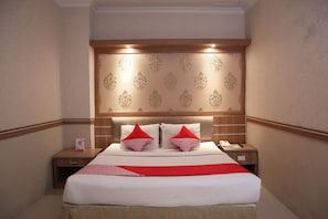 A hotel room with a large bed, two bedside tables, a wooden headboard, and a red throw blanket. - OYO 742 Mona Plaza Hotel (Pekanbaru)