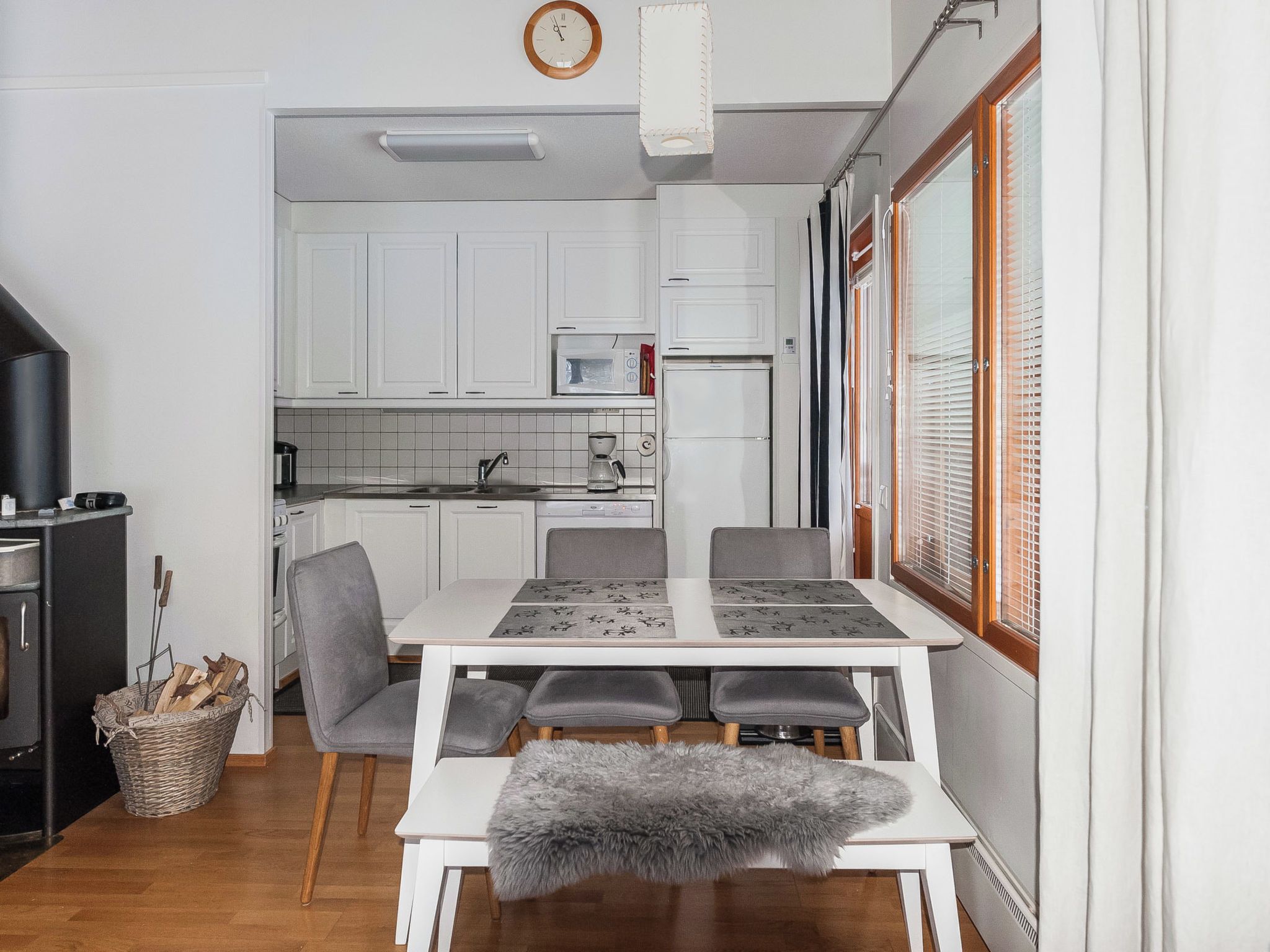 Une cuisine compacte avec des meubles blancs, un four à micro-ondes et un coin repas comprenant une table et des chaises.