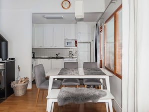 Cocina compacta con gabinetes blancos, un microondas y una zona de comedor con mesa y sillas.