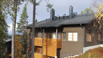 Une maison moderne à deux étages, dotée d’un toit en pente, de grandes fenêtres et d’un balcon en bois.