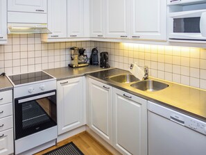 A kitchen with white cabinets, a stainless steel sink, a coffee maker, and a dishwasher.