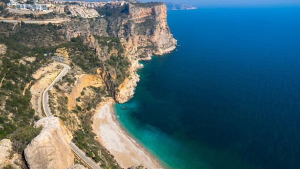 Une falaise côtière avec une route sinueuse et une plage.