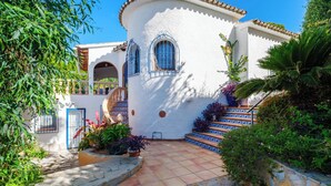 Un bâtiment blanc agrémenté de touches de bleu, avec un escalier et une végétation luxuriante tout autour.