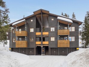 Un immeuble à plusieurs étages doté d’une entrée centrale, de balcons et d’un toit en pente.