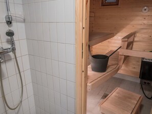 Un intérieur en bois avec une douche, une étagère avec un pot et une petite table.