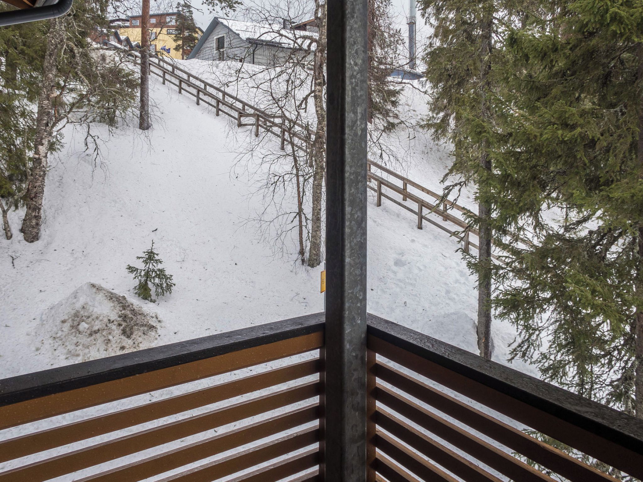 Lumipeitteinen ulkoalue, jolta johtaa ylös puinen portaikko.