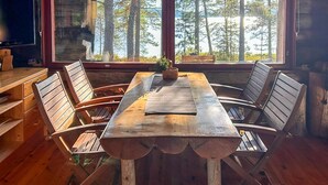 Une table de salle à manger en bois, avec quatre chaises, une petite plante et un carnet posés dessus.
