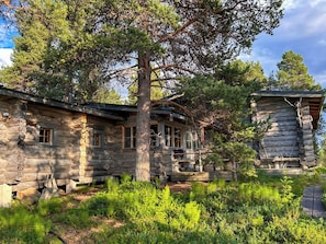 A rustic log cabin with a large tree in front, surrounded by lush greenery. - Nanguvilla by Interhome (Inari)