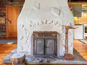 A stone fireplace with a metal door, surrounded by a rustic stone wall with carved patterns. - Nanguvilla by Interhome (Inari)