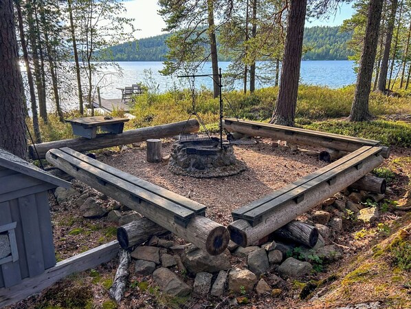 A campsite with a fire pit surrounded by logs, a table, and a bench.