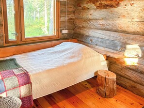 A cozy cabin room with a bed, a window, and a wooden wall.