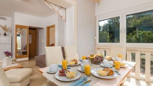 A breakfast table set with plates of food, glasses of orange juice, and a view of greenery outside. - Apartment Mare 5 by Interhome (Rab/Kampor)