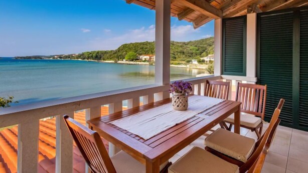 A wooden deck with a table and chairs overlooking a coastal view. - Apartment Mare 5 by Interhome (Rab/Kampor)