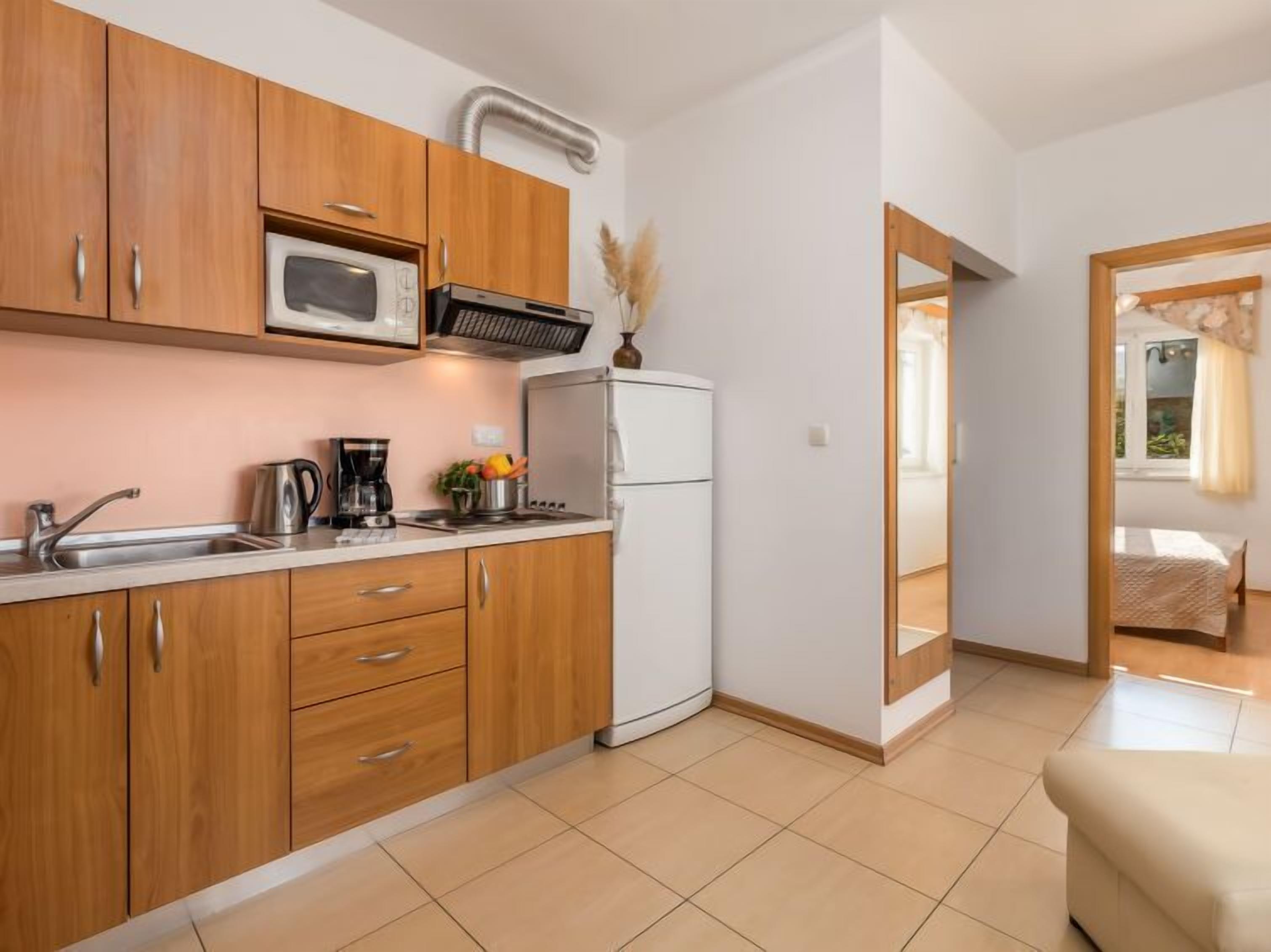 A compact kitchen with wooden cabinets, a microwave, a coffee maker, and a refrigerator.