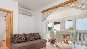 A modern living room with a sofa, a coffee table, and a dining area with chairs and a table. - Apartment Mare 5 by Interhome (Rab/Kampor)