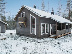 Een chalet met twee verdiepingen, een balkon, grote ramen en een overdekte veranda.