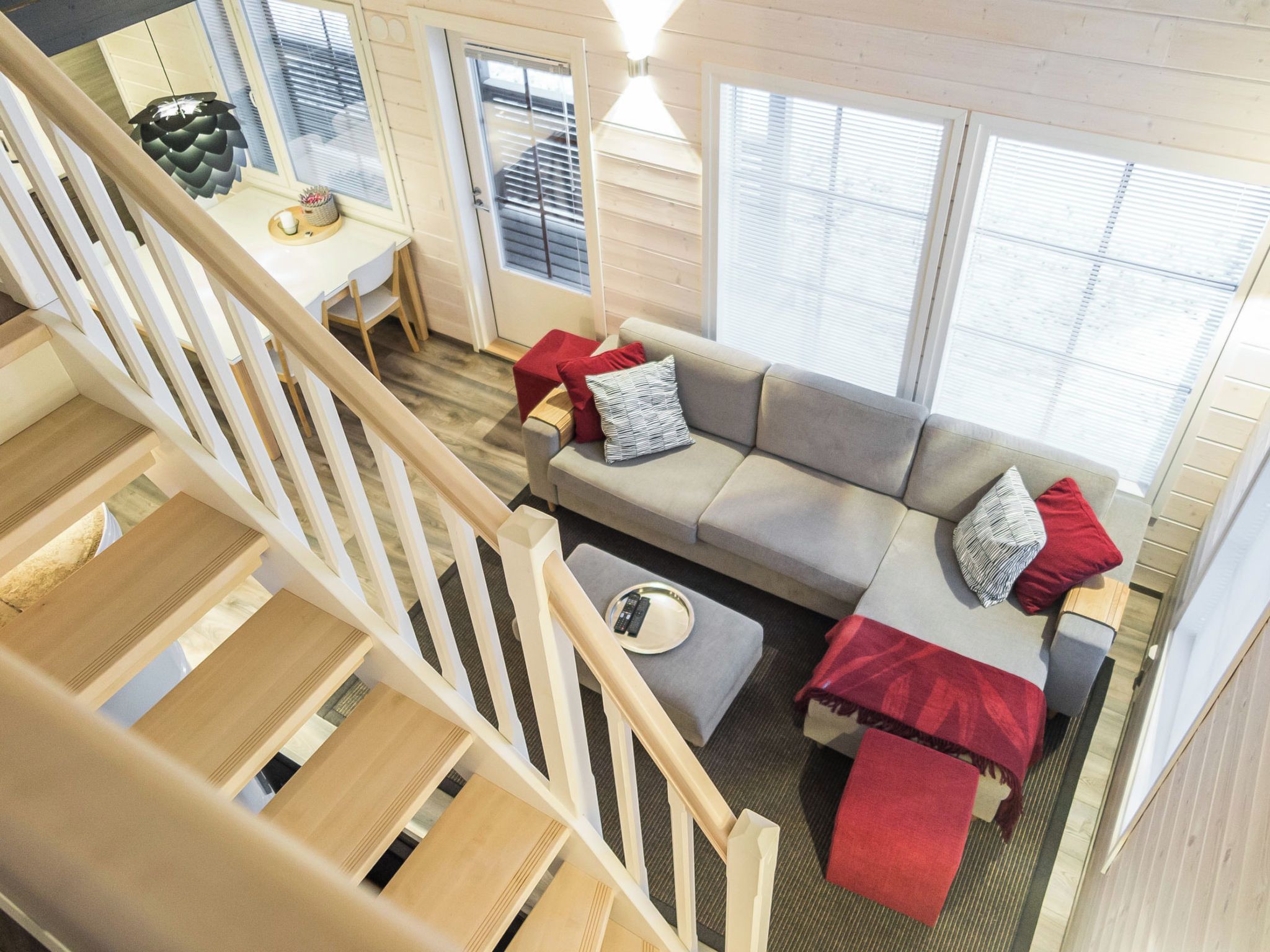 Een modern interieur met een trap, een zithoek, een eethoek en grote ramen.