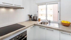 A modern kitchen with white cabinets, a stainless steel sink, and a window providing natural light.