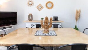A dining area with a wooden table, chairs, a television, and decorative wall art.
