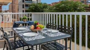 An outdoor dining area with a table set for two, surrounded by a white railing.