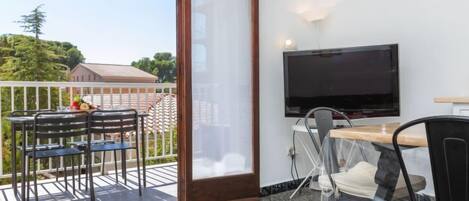 A balcony with a table and chairs, a TV, and a sliding glass door.