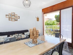 Ein Essbereich mit Holztisch, Stühlen, einer gewebten Korbschale als Mittelpunkt und Blick auf den Balkon.