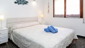 A bedroom with a bed, a nightstand, a lamp, a wall decoration, and a window.