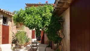 A courtyard with a table and chairs, a potted plant, and a red door. - Les Huppes by Interhome (Saint Saturnin d'Apt)