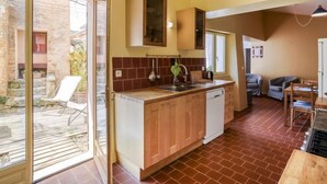 A kitchen with wooden cabinets, a built-in dishwasher, and a large window. - Les Huppes by Interhome (Saint Saturnin d'Apt)