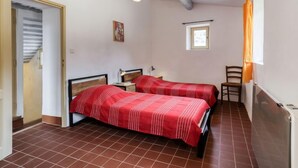 A bedroom with two beds, a small window, and a door leading to a staircase. - Les Huppes by Interhome (Saint Saturnin d'Apt)
