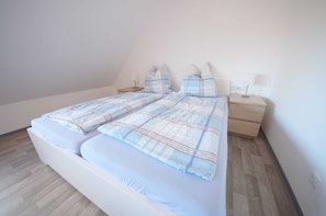Een slaapkamer met een bed, twee nachtkastjes en een bedbank.