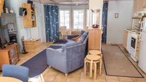 A cozy living room with a sofa, a TV, and a fireplace. There is a kitchen area with a stove and sink. - Nelikko b by Interhome (Kuusamo)