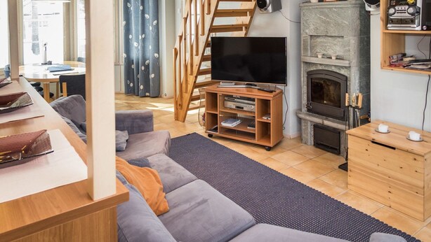 A cozy living room with a sofa, TV, fireplace, and wooden staircase. - Nelikko b by Interhome (Kuusamo)